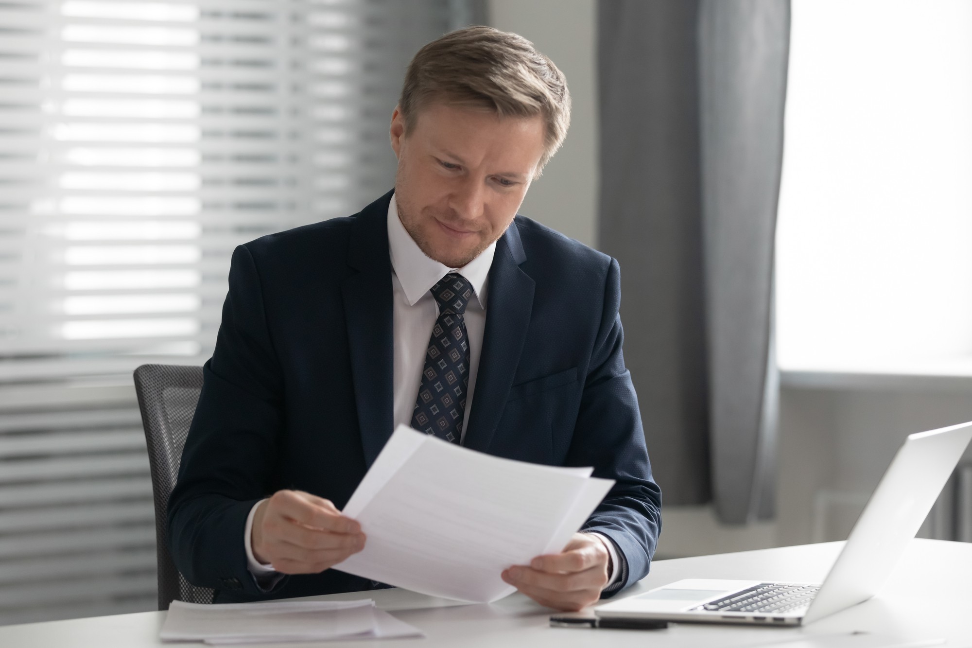 Man in a suit intently reading a document