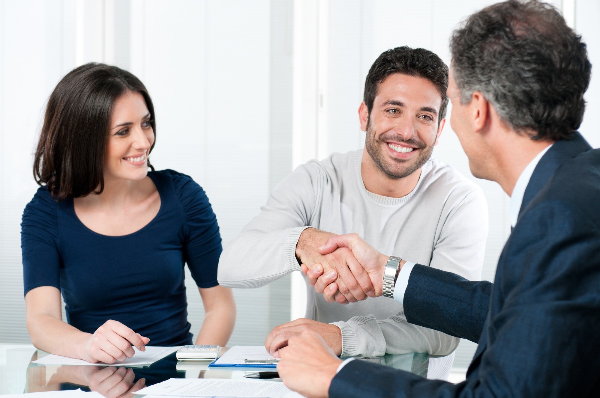 Man and woman shake hands with a man in suit